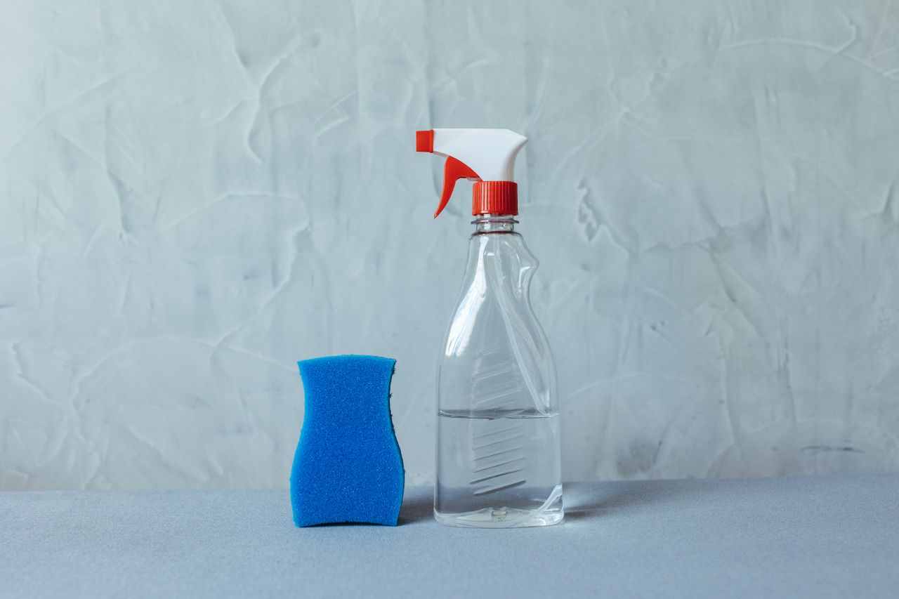 digital A spray bottle and blue sponge on a textured grey surface. Perfect for cleaning themes.