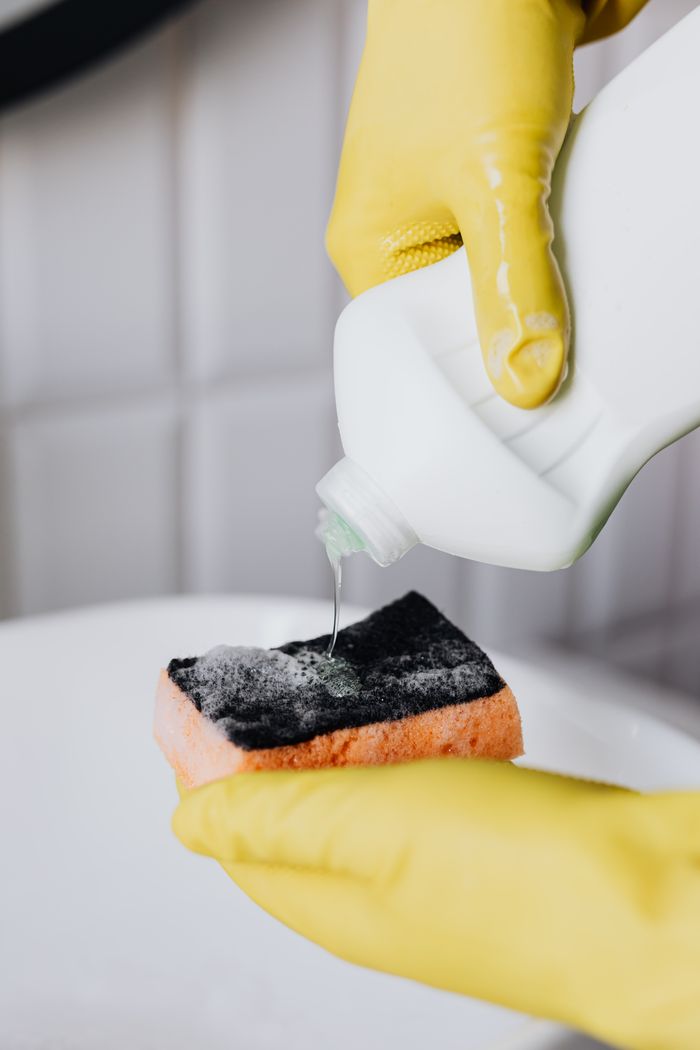 why-choose-us Crop faceless person in yellow latex protective gloves pouring cleaning agent from bottle to sponge in bathroom