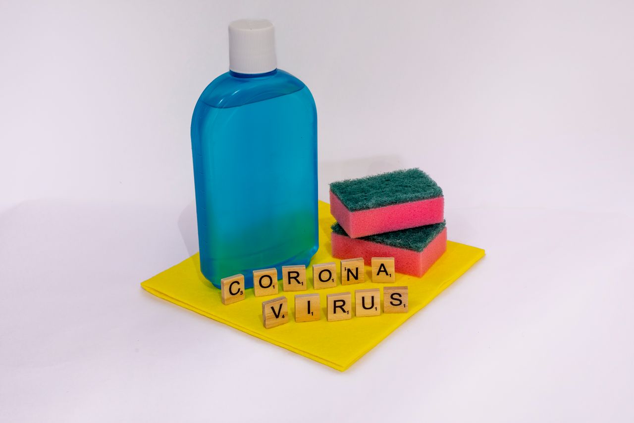 creative-02 Cleaning products with scrabble tiles spelling coronavirus on a white surface.
